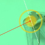 Imagen anatómica de un hombro humano con fondo verde, flecha roja apuntando a la articulación glenohumeral y líneas de referencia en blanco y amarillo.