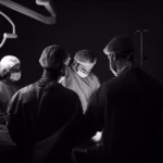 Un grupo de cirujanos en una sala de operaciones, iluminados por luces quirúrgicas, realizando una cirugía con concentración y precisión.