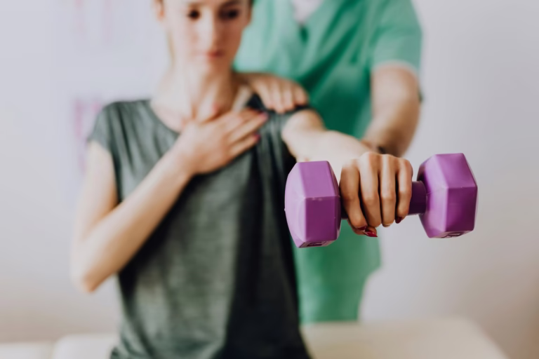 Mujer realizando ejercicios de rehabilitación con una pesa morada, asistida por un fisioterapeuta en un entorno clínico.